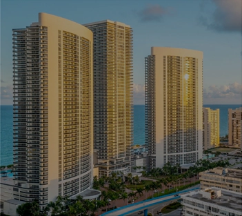 High-angle aerial view of modern coastal high-rise luxury apartment towers next to the ocean.
